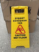 Sürüşkən yer xəbərdarlıq lövhəsi – “Diqqət: Sürüşkən yer / Caution Wet — Orxan