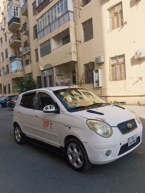 Kia Picanto, ağ rəng, hetçbek gövdə. Xüsusiyyətlər: - Kompakt şəhər — Bakı