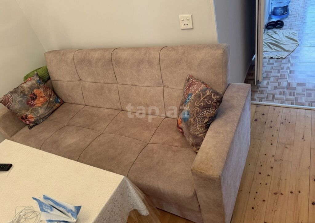 Bej rəngli, kompakt 3 nəfərlik divan. Yumşaq, toxumalı parça üzlük və